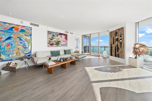 living room featuring hardwood / wood-style flooring, floor to ceiling windows, and a water view