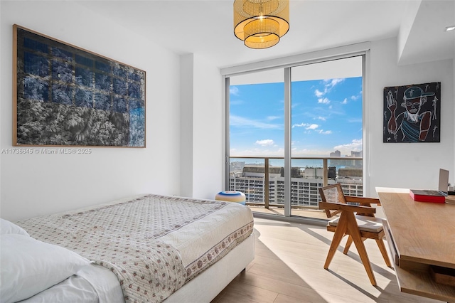 bedroom featuring access to exterior, wood-type flooring, floor to ceiling windows, and a water view