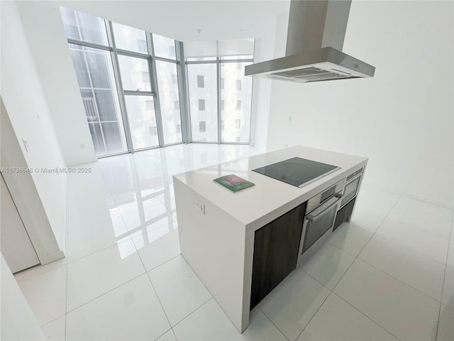 kitchen with floor to ceiling windows, stainless steel oven, island range hood, a center island, and black electric stovetop