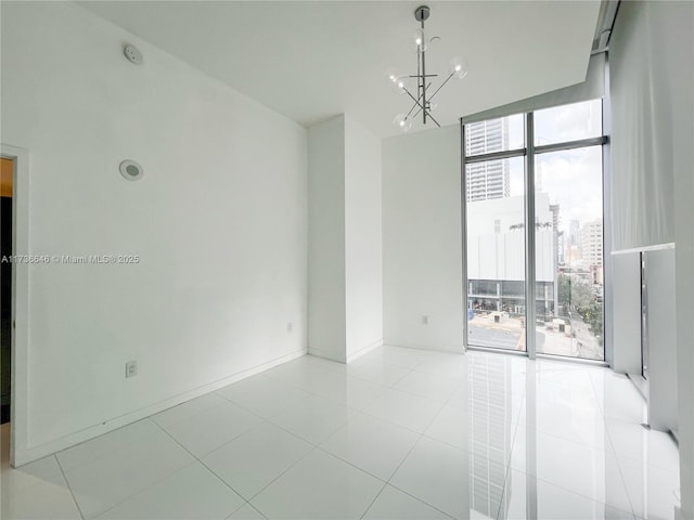 tiled spare room featuring floor to ceiling windows and a chandelier