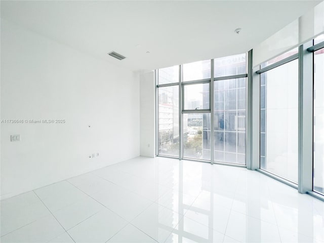 tiled empty room featuring a wall of windows