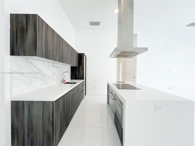 kitchen featuring island range hood, tasteful backsplash, sink, light tile patterned floors, and black electric cooktop