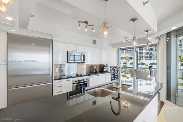 kitchen featuring sink, pendant lighting, stainless steel appliances, decorative backsplash, and white cabinets