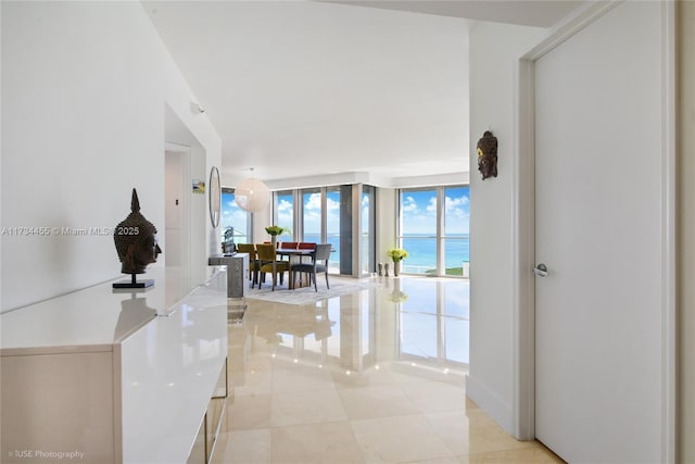 hall with a water view, a wall of windows, and light tile patterned flooring