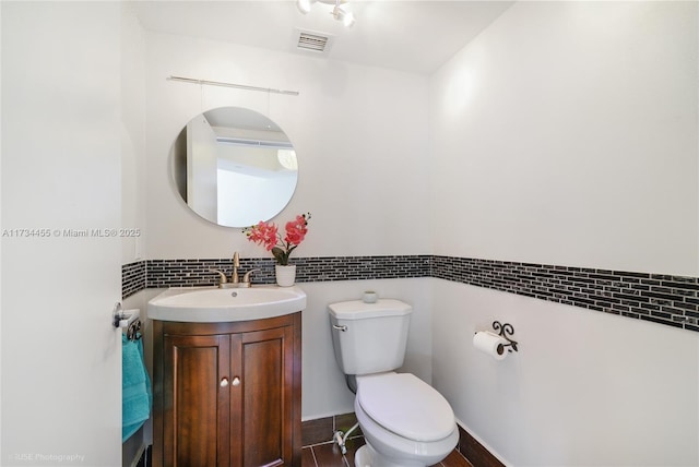 bathroom featuring vanity, decorative backsplash, and toilet