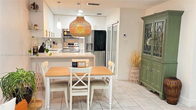 kitchen featuring decorative light fixtures, stainless steel appliances, visible vents, light countertops, and a peninsula