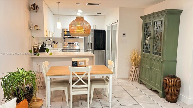 kitchen featuring stainless steel appliances, sink, white cabinets, and decorative light fixtures