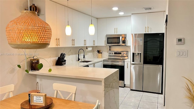 kitchen featuring appliances with stainless steel finishes, decorative light fixtures, sink, white cabinets, and kitchen peninsula