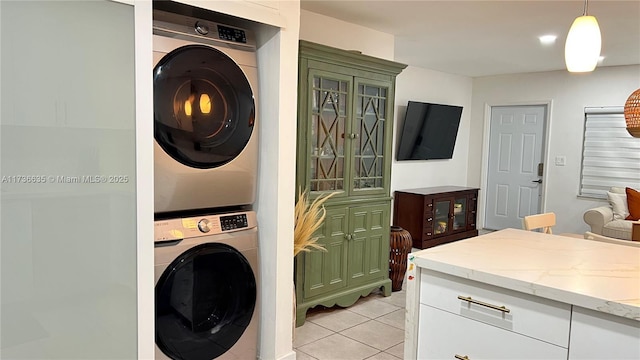 washroom featuring laundry area, light tile patterned flooring, and stacked washer and clothes dryer