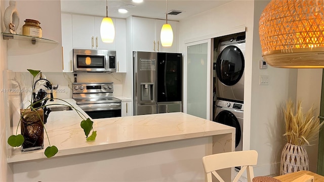 kitchen featuring visible vents, white cabinets, appliances with stainless steel finishes, light stone countertops, and stacked washing maching and dryer