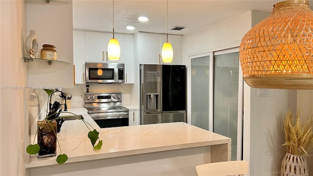 kitchen featuring decorative light fixtures, kitchen peninsula, stainless steel appliances, light stone countertops, and white cabinets