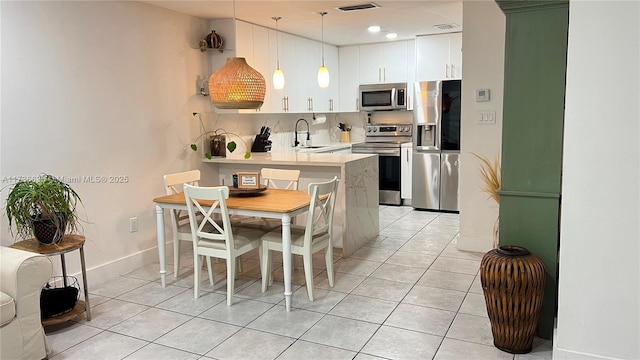 kitchen with sink, stainless steel appliances, white cabinets, decorative light fixtures, and kitchen peninsula