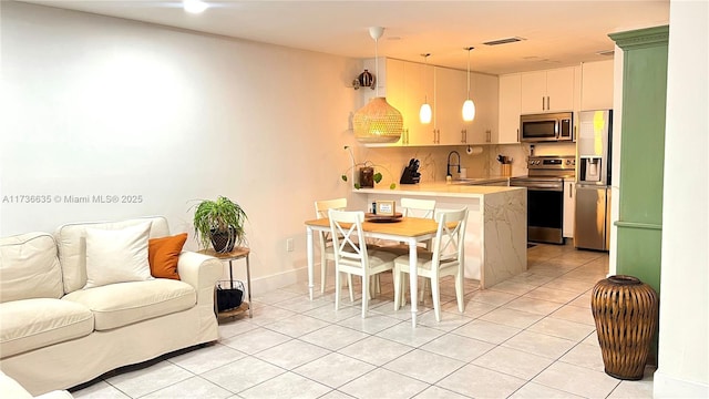 kitchen with appliances with stainless steel finishes, pendant lighting, sink, light tile patterned floors, and kitchen peninsula