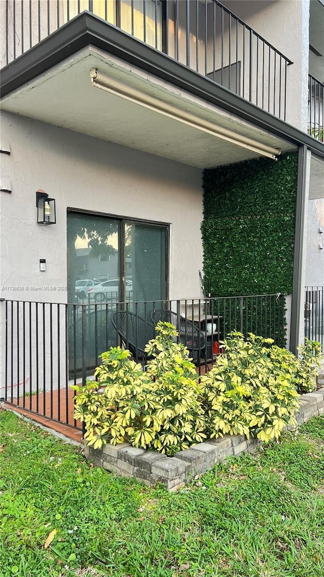 entrance to property featuring fence, board and batten siding, and stucco siding