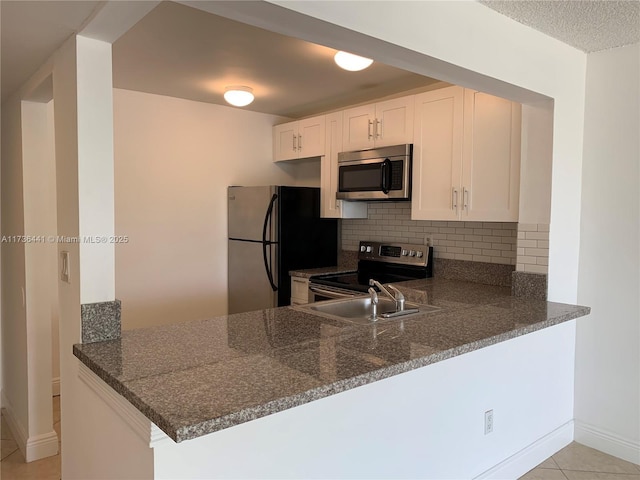 kitchen featuring white cabinetry, stainless steel appliances, kitchen peninsula, and decorative backsplash