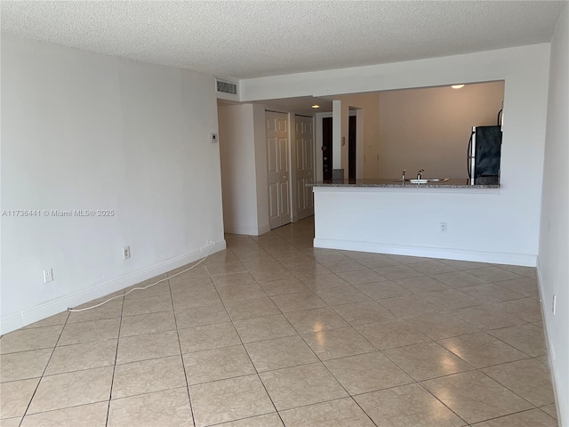 tiled empty room featuring sink and a textured ceiling