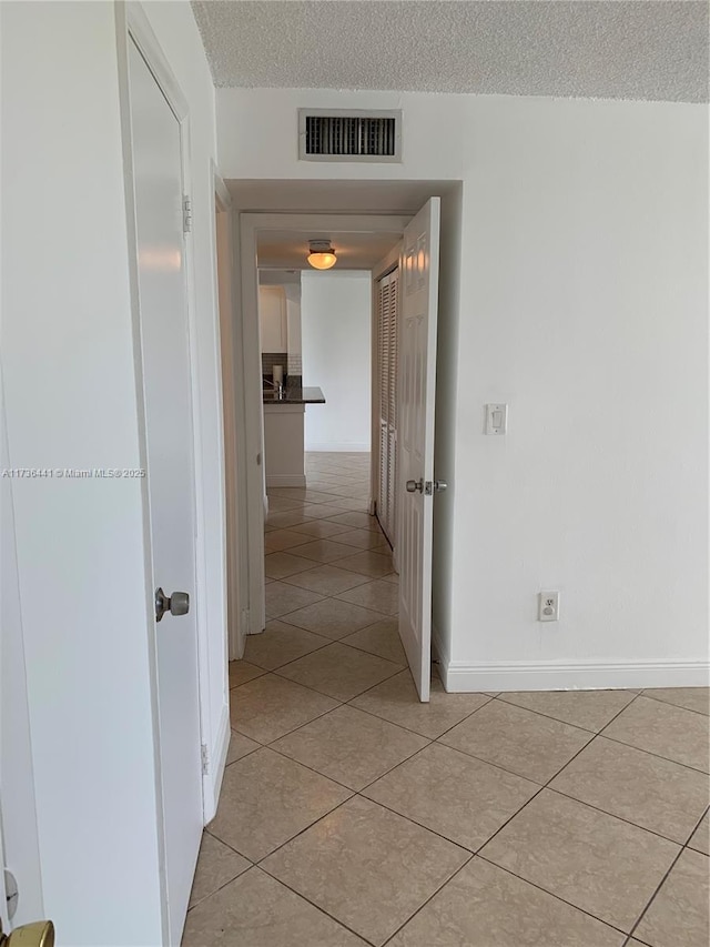 hall with light tile patterned flooring and a textured ceiling