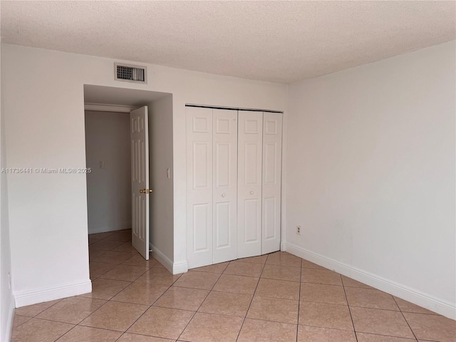 unfurnished bedroom with a closet, a textured ceiling, and light tile patterned flooring