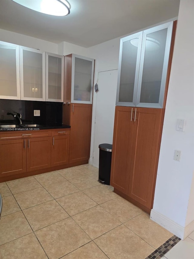 kitchen featuring tasteful backsplash, sink, and light tile patterned flooring