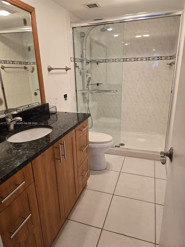 bathroom featuring tile patterned flooring, vanity, toilet, and an enclosed shower