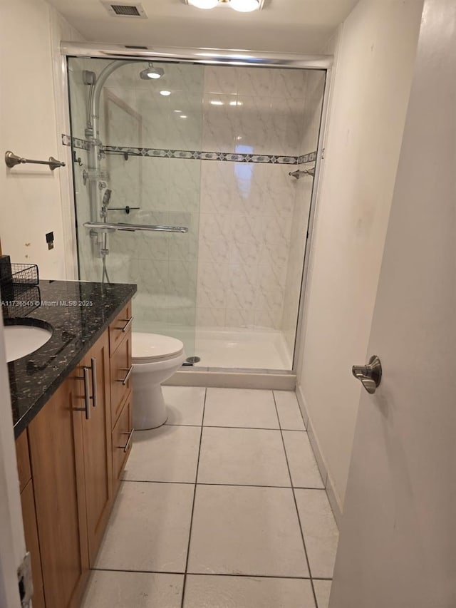 bathroom featuring a shower with door, vanity, tile patterned floors, and toilet