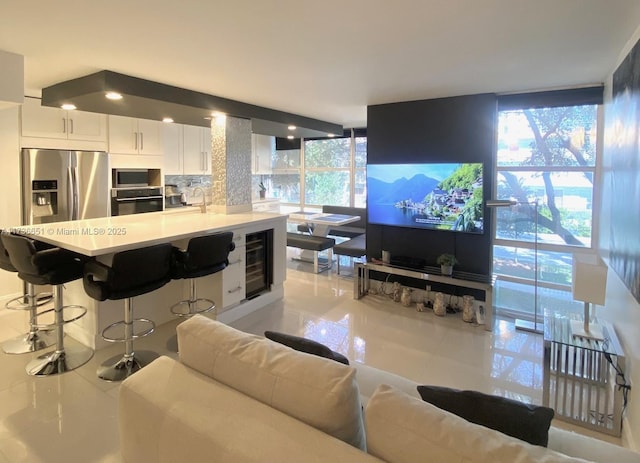 living room featuring sink, floor to ceiling windows, and beverage cooler