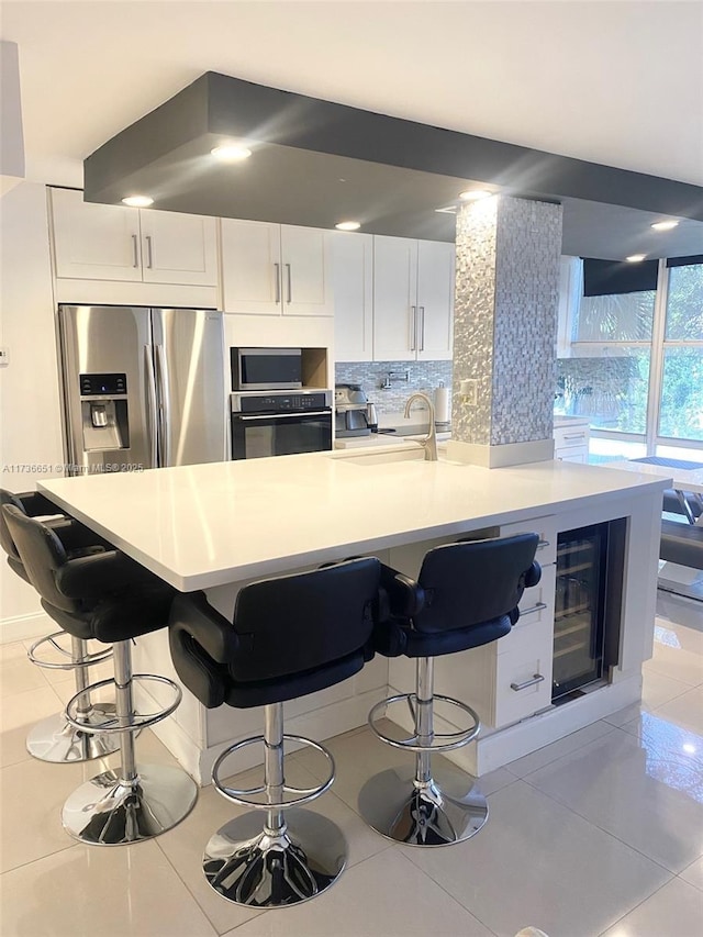 kitchen with appliances with stainless steel finishes, tasteful backsplash, sink, white cabinets, and beverage cooler