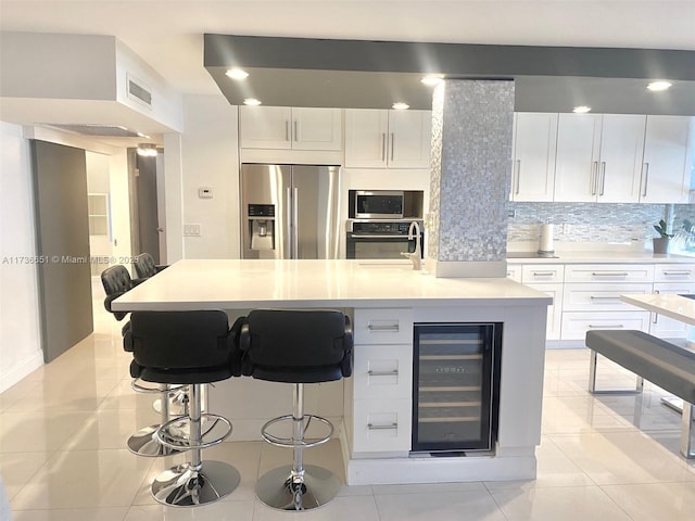 kitchen featuring stainless steel appliances, white cabinetry, wine cooler, and decorative backsplash