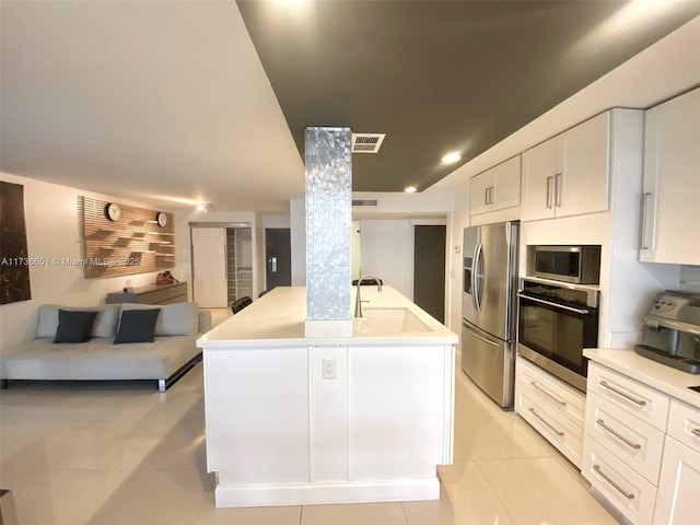 kitchen featuring appliances with stainless steel finishes, white cabinetry, an island with sink, sink, and light tile patterned floors