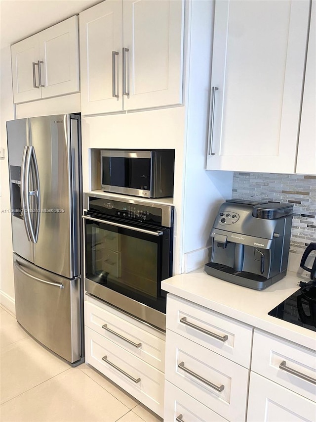 kitchen featuring white cabinetry, appliances with stainless steel finishes, decorative backsplash, and light tile patterned floors