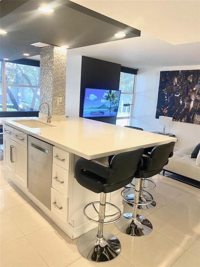 bar featuring light tile patterned floors, dishwasher, sink, and white cabinets