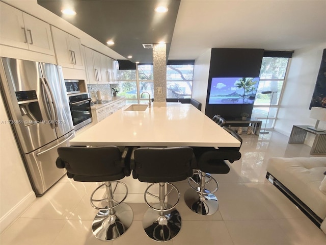 kitchen with sink, stainless steel appliances, a kitchen breakfast bar, and white cabinets