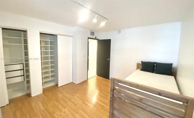 bedroom featuring rail lighting and light hardwood / wood-style floors