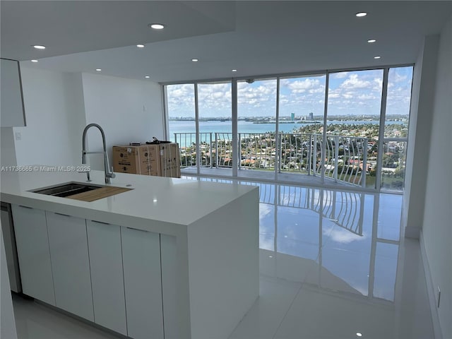 kitchen featuring a water view, a sink, floor to ceiling windows, plenty of natural light, and modern cabinets