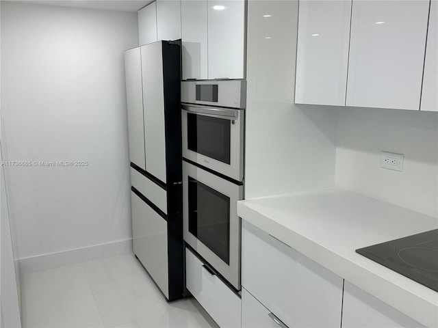 kitchen featuring modern cabinets, fridge, light countertops, white cabinets, and black electric stovetop