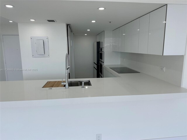 kitchen featuring recessed lighting, visible vents, a sink, modern cabinets, and black electric cooktop