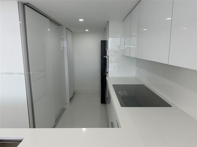 kitchen featuring light countertops, modern cabinets, black electric stovetop, and white cabinets