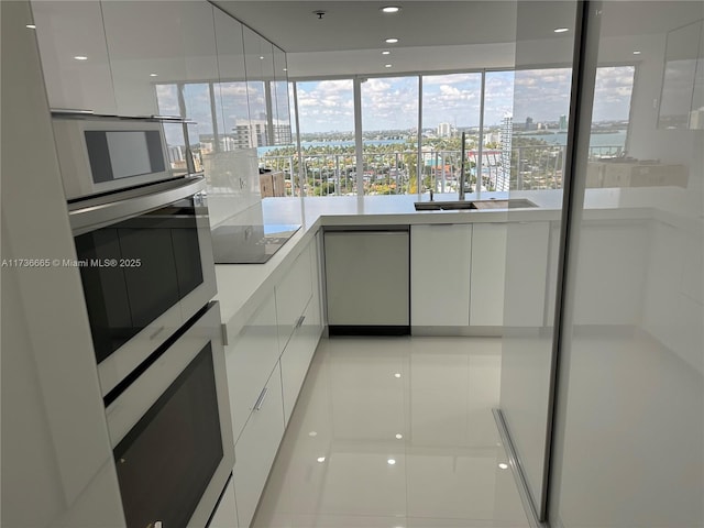 kitchen with oven, white cabinets, light countertops, a view of city, and modern cabinets