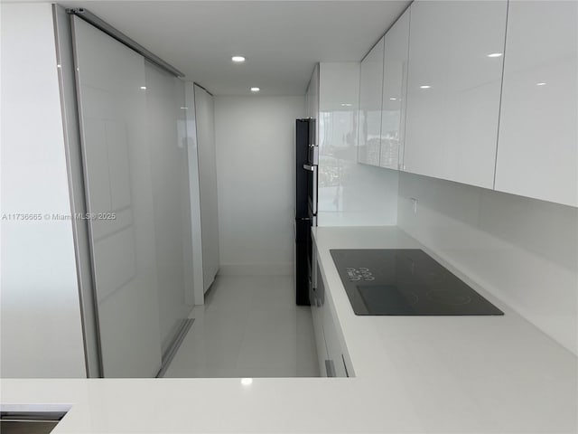 kitchen featuring light countertops, modern cabinets, black electric cooktop, and white cabinetry