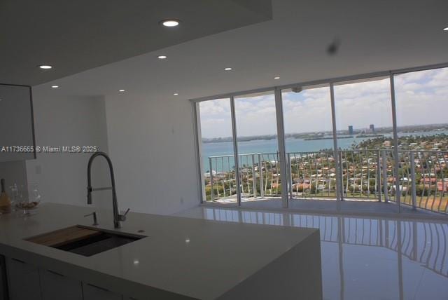 kitchen featuring a sink, a water view, recessed lighting, and expansive windows