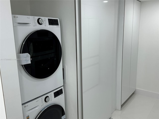 clothes washing area featuring laundry area, baseboards, and stacked washer / drying machine