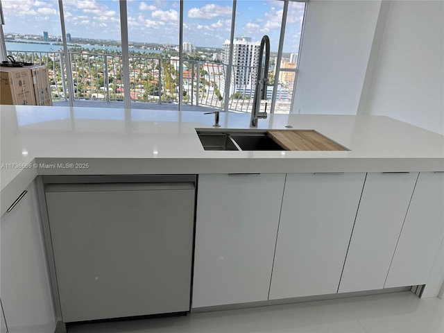 kitchen featuring dishwasher, modern cabinets, light countertops, a city view, and white cabinetry