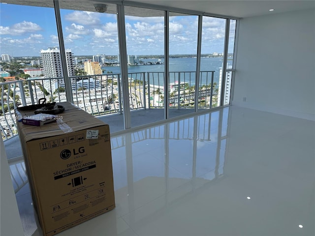 empty room featuring expansive windows, a water view, and a view of city