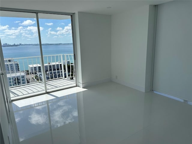 spare room with a water view and baseboards