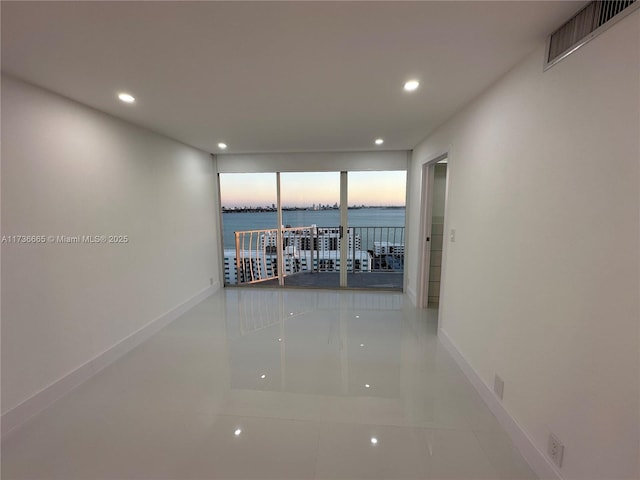 corridor with recessed lighting, visible vents, a water view, and baseboards