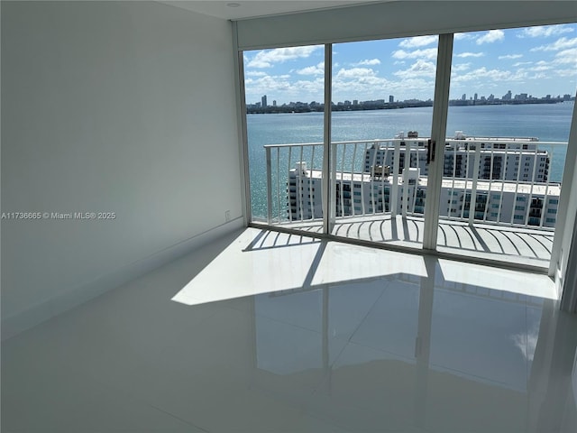 spare room with a view of city, a water view, and tile patterned floors