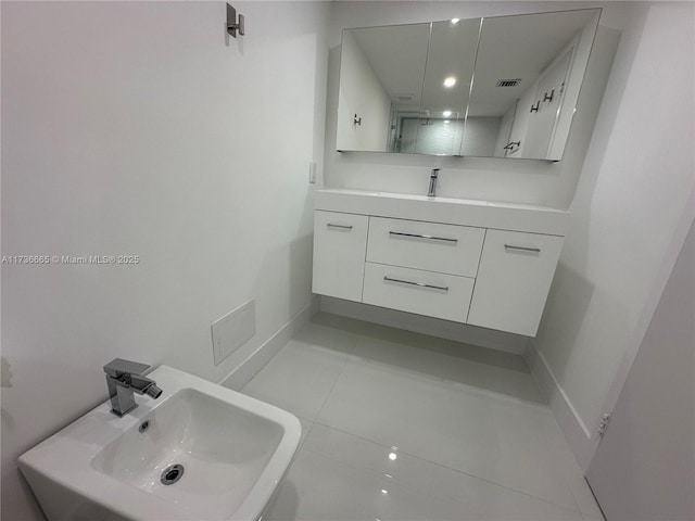 bathroom with tile patterned flooring, visible vents, a sink, and baseboards