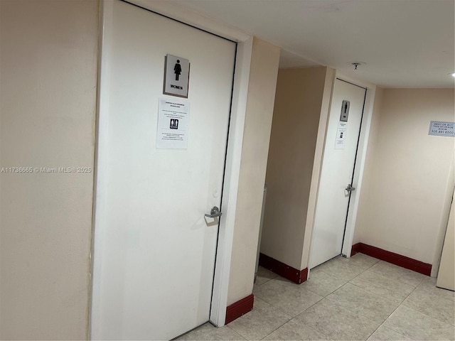 corridor with light tile patterned flooring and baseboards