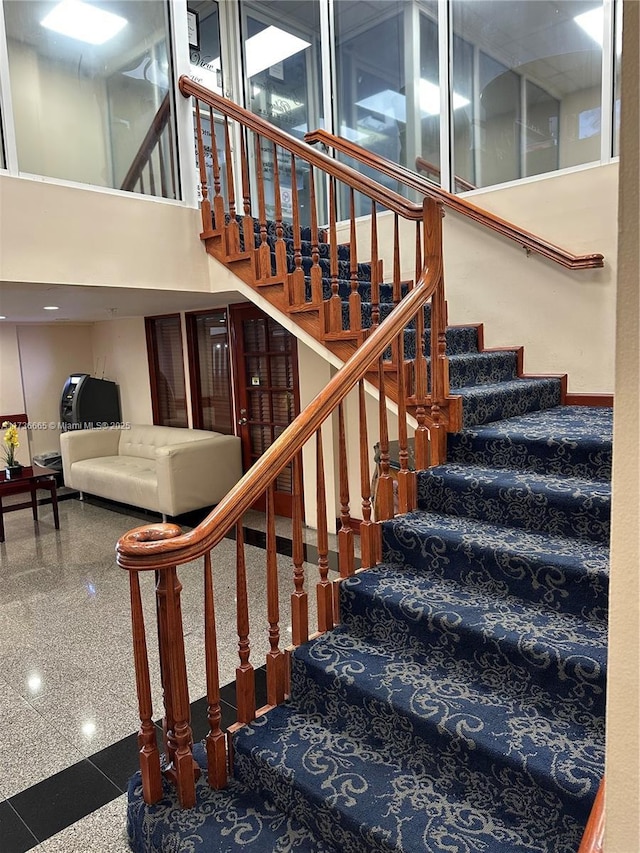 stairway featuring a high ceiling and granite finish floor