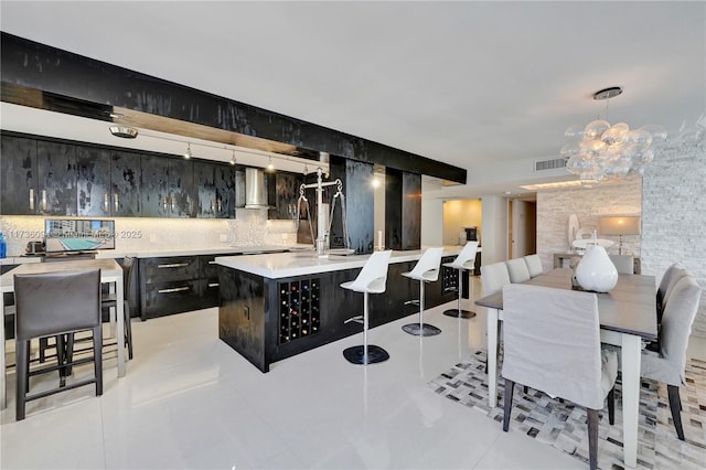 interior space with pendant lighting, wall chimney range hood, light tile patterned floors, and backsplash